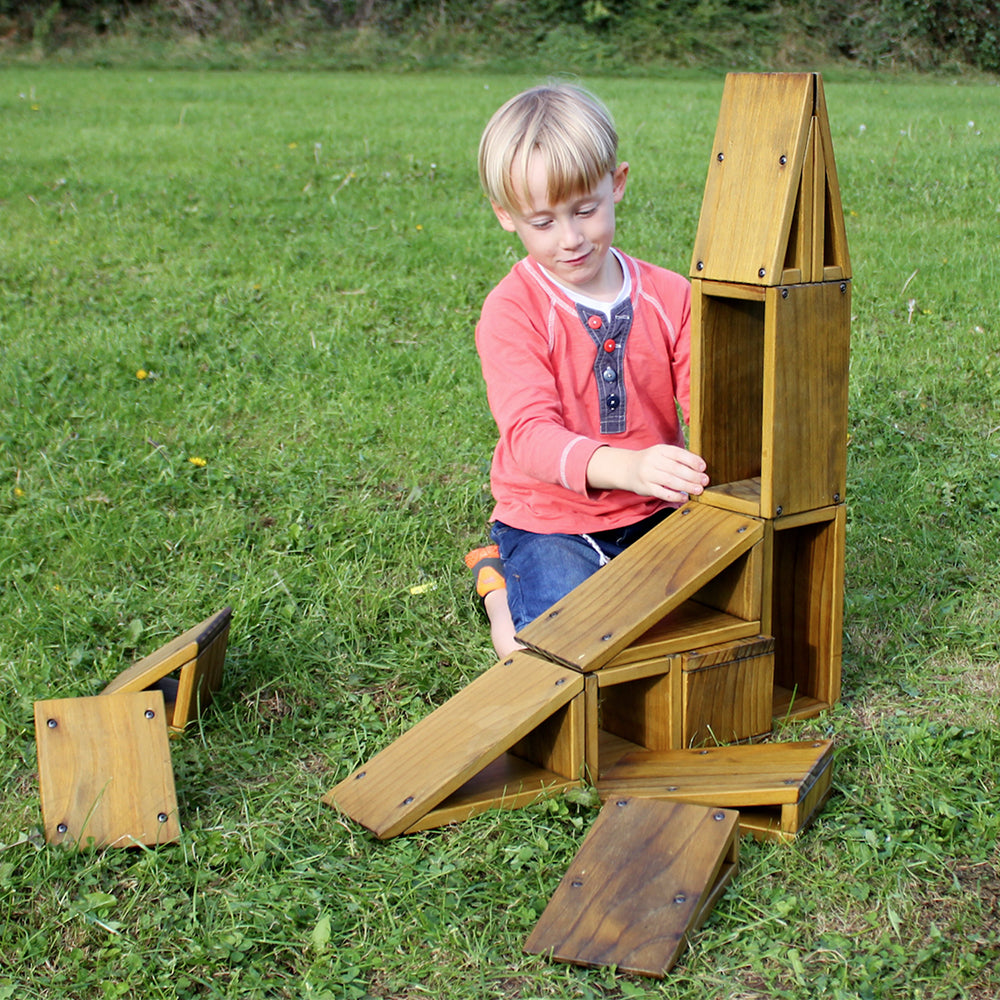 Children building structures with outdoor hollow wooden blocks