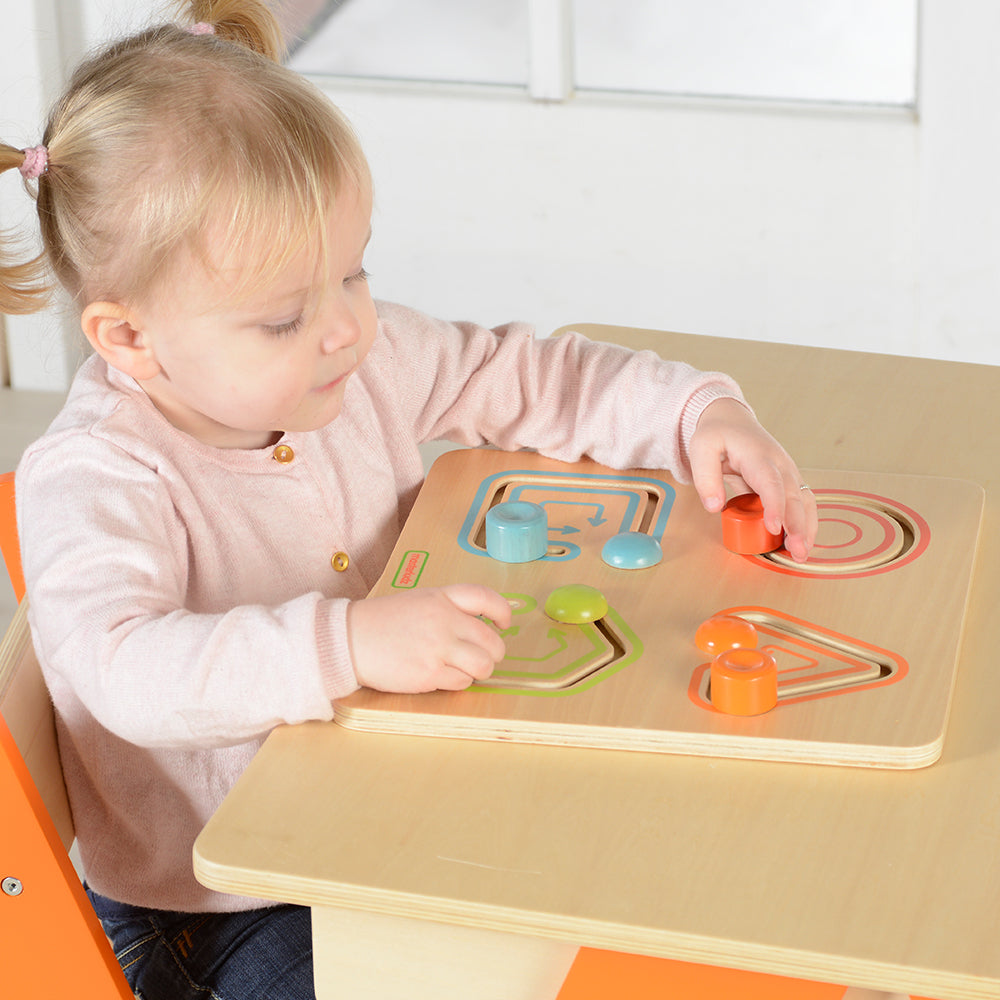 Close-up of wooden geometric blocks moving along arrows for motor skill training.