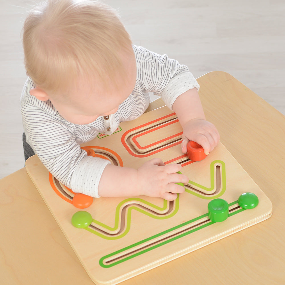 Close-up of toddler moving wooden blocks along sliding tracks for motor skill development