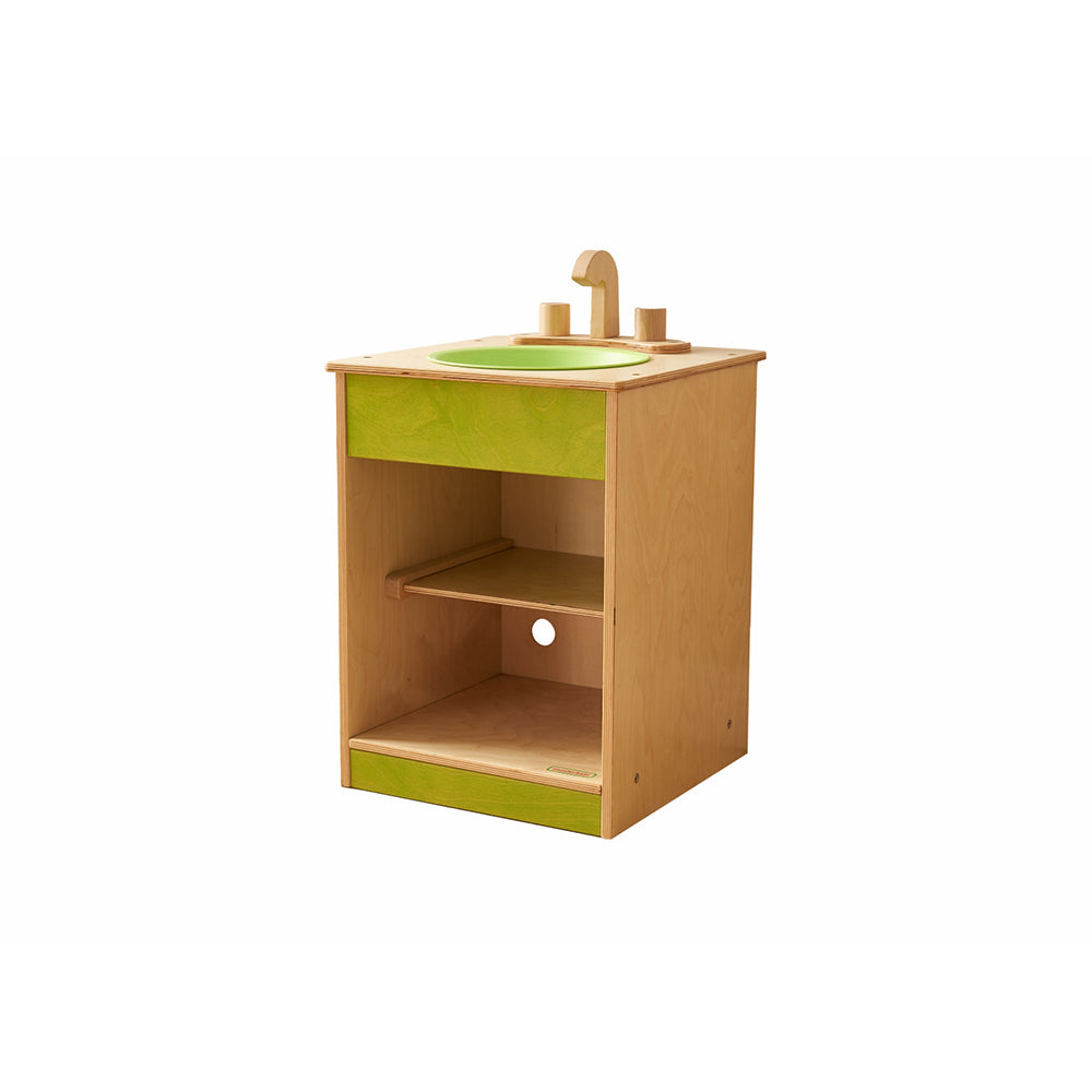 Toddler washing play food and utensils in wooden sink unit.
