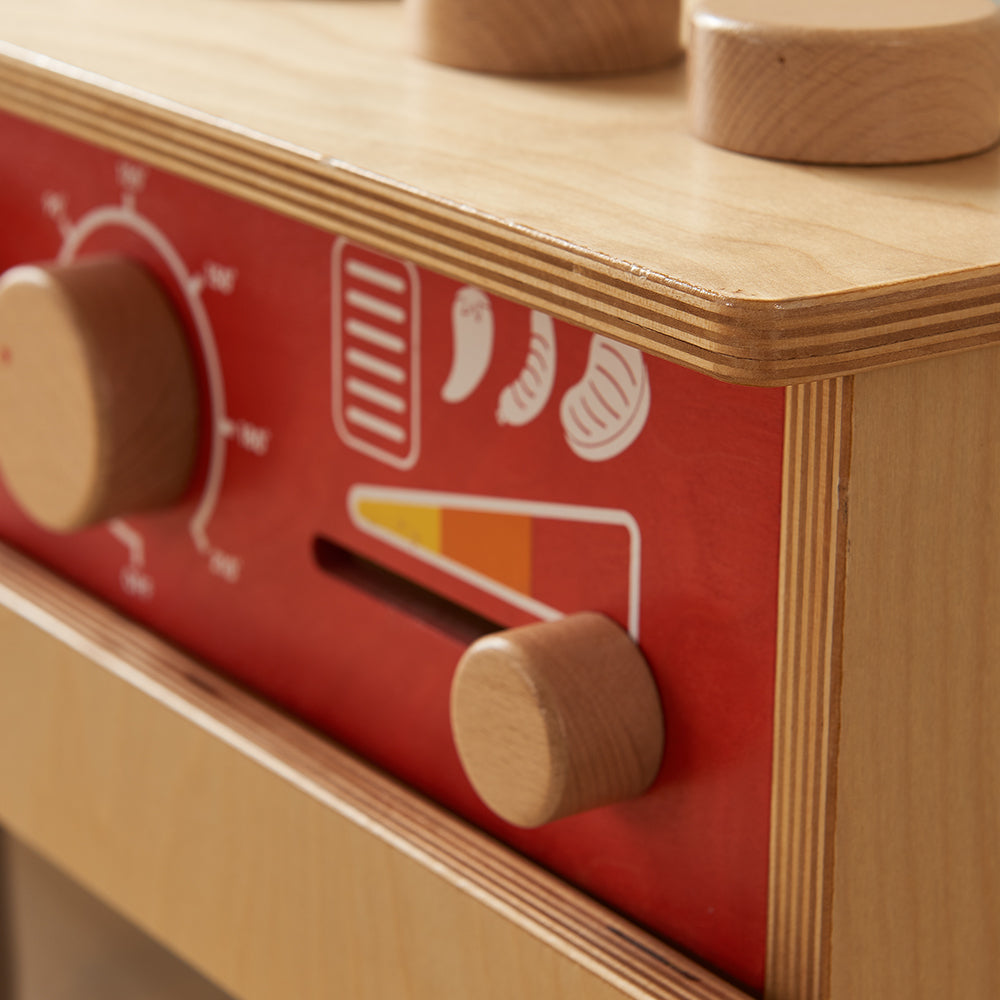Toddler engaging in imaginative cooking play with pastel wooden unit.