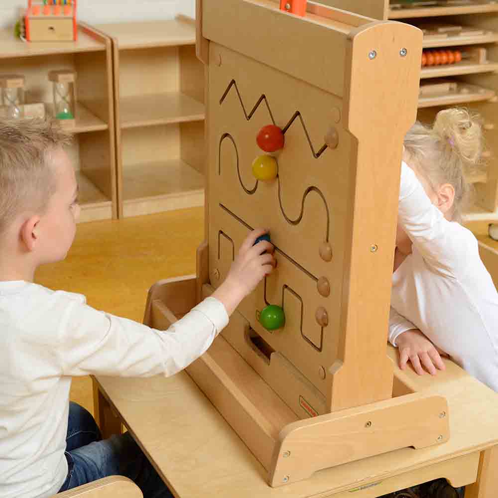 Child practicing hand-eye coordination on wooden educational board.