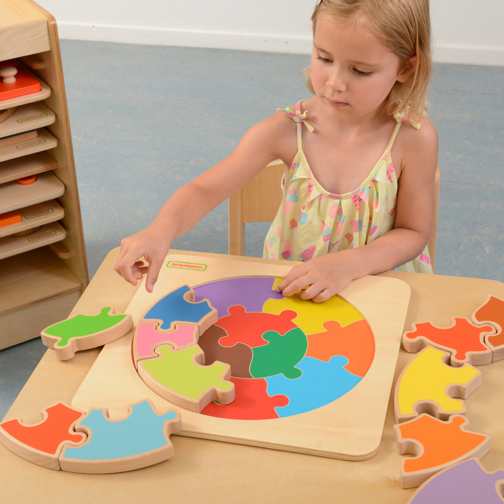 Children assembling oversized wooden puzzle on colour-guided tray.