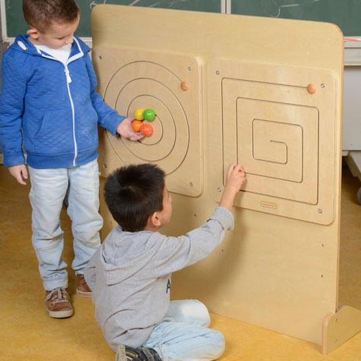 Children sliding shapes through durable wooden maze board in classroom.