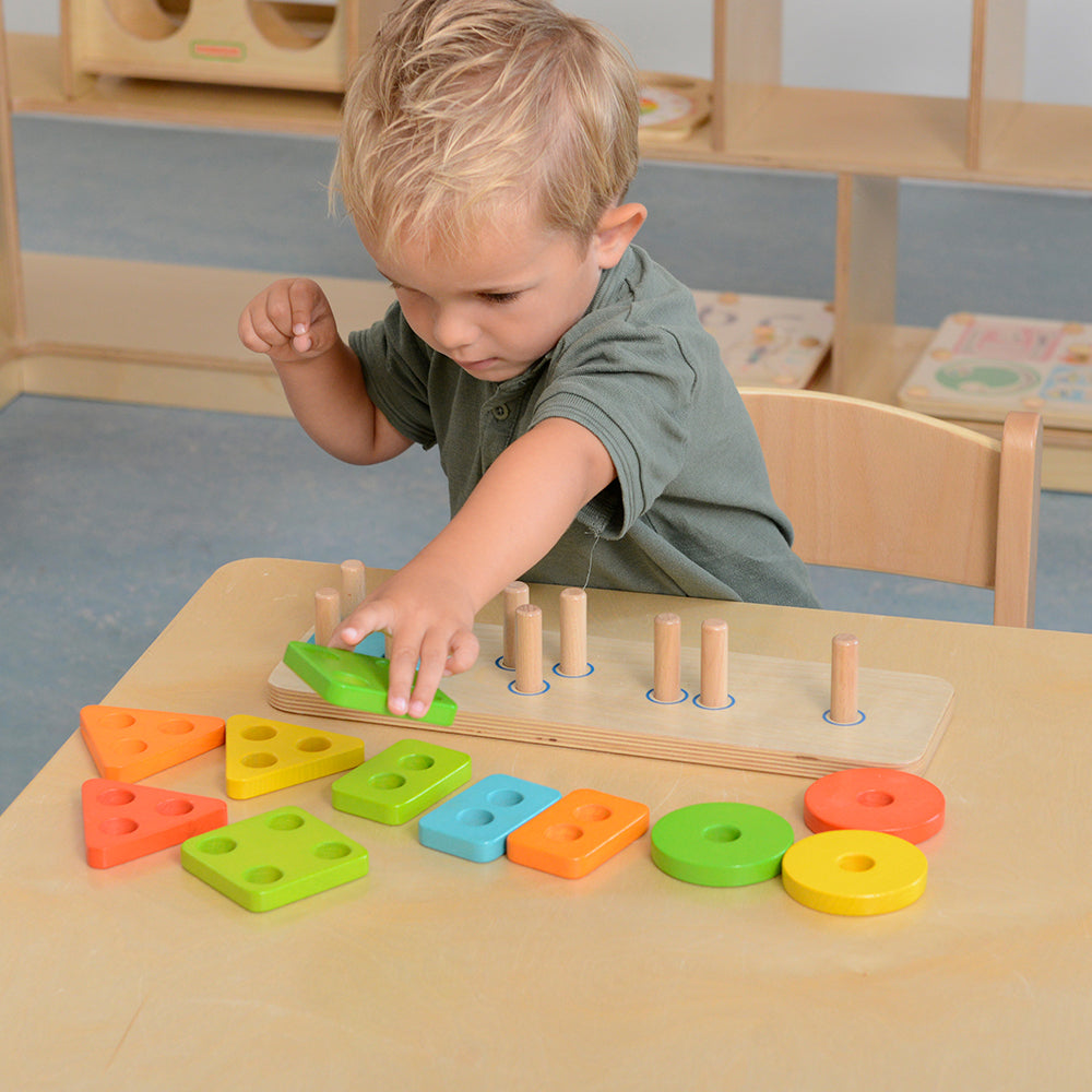 Children building and stacking shapes on wooden pegboard