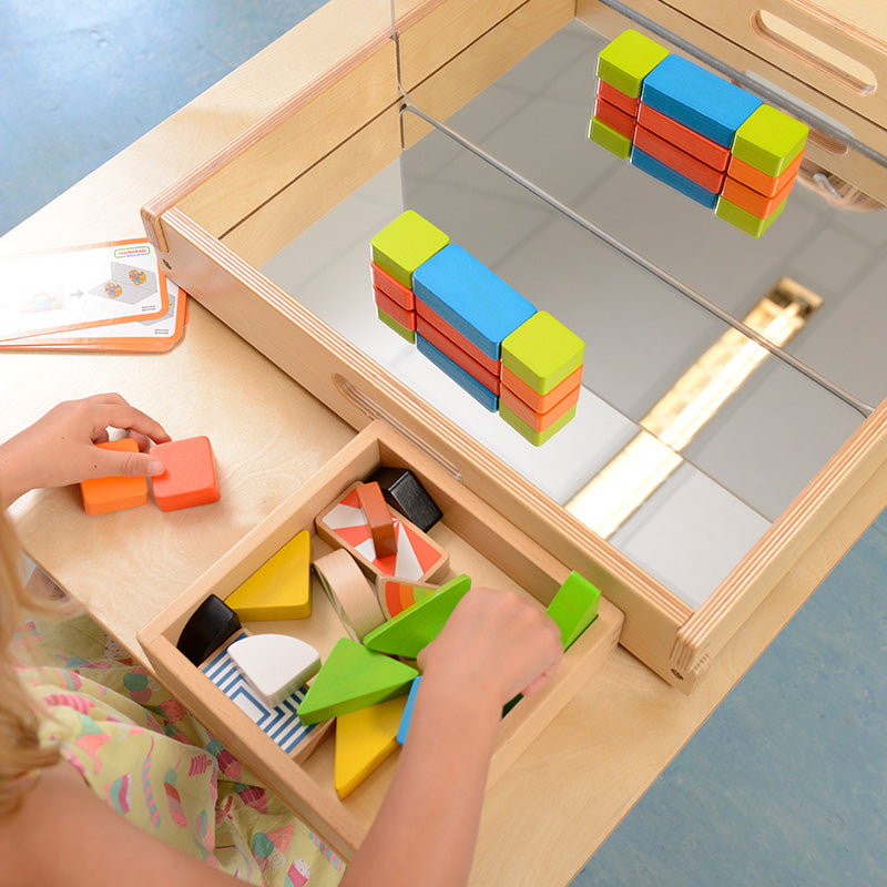 Children experimenting with shapes and patterns in mirror tray