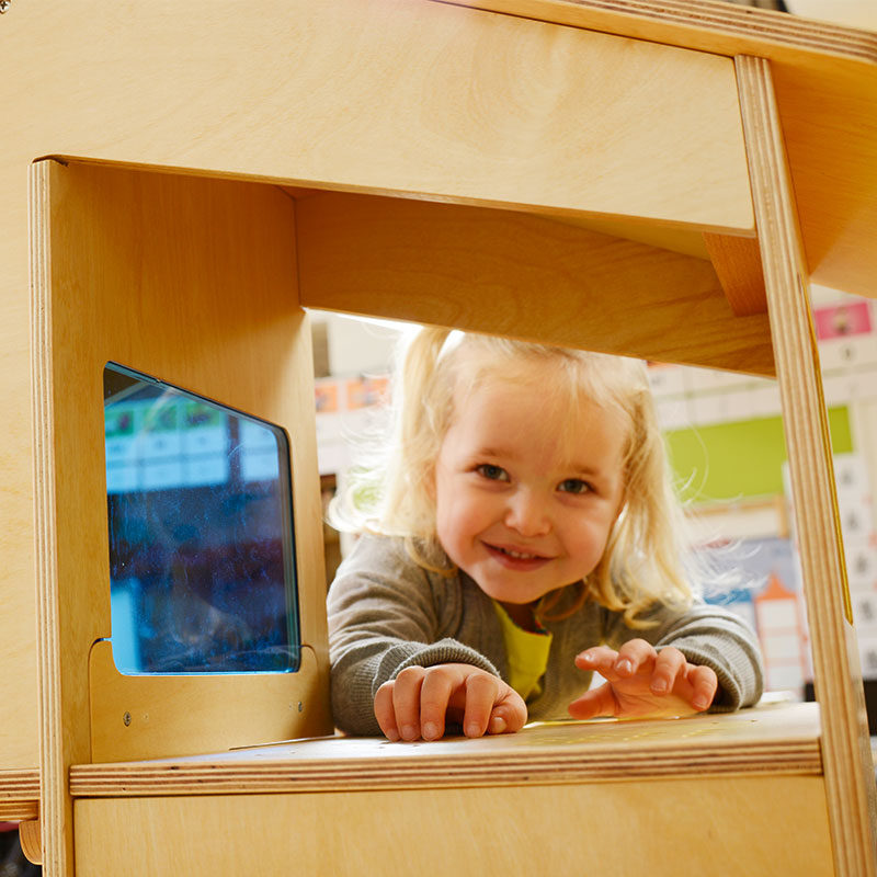 Children exploring reflections in the mirror room of the wooden sensory house