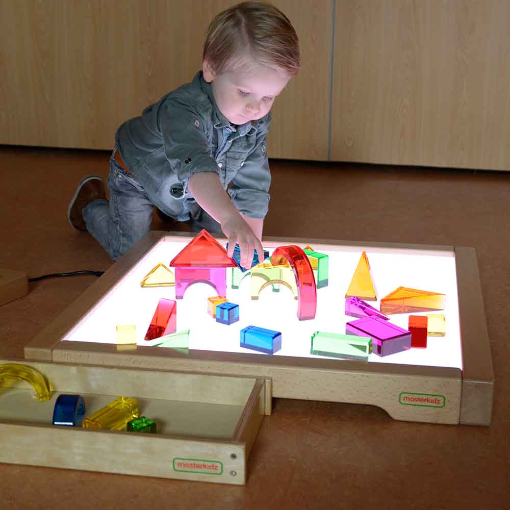 Children exploring colour mixing with translucent blocks on LED light box