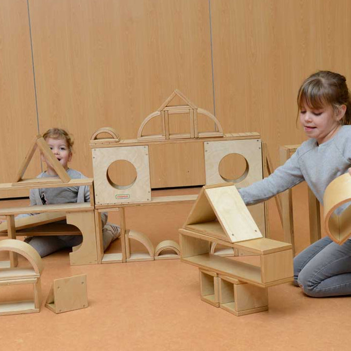 Children playing with Masterkidz plywood hollow blocks to build castles, ramps, and towers, promoting teamwork and spatial awareness