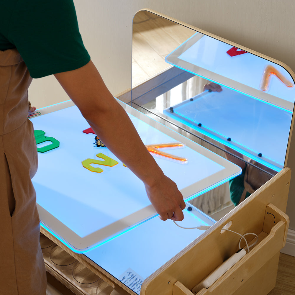 Detail of the multi-compartment shelving on the Masterkidz table organized with educational loose parts.