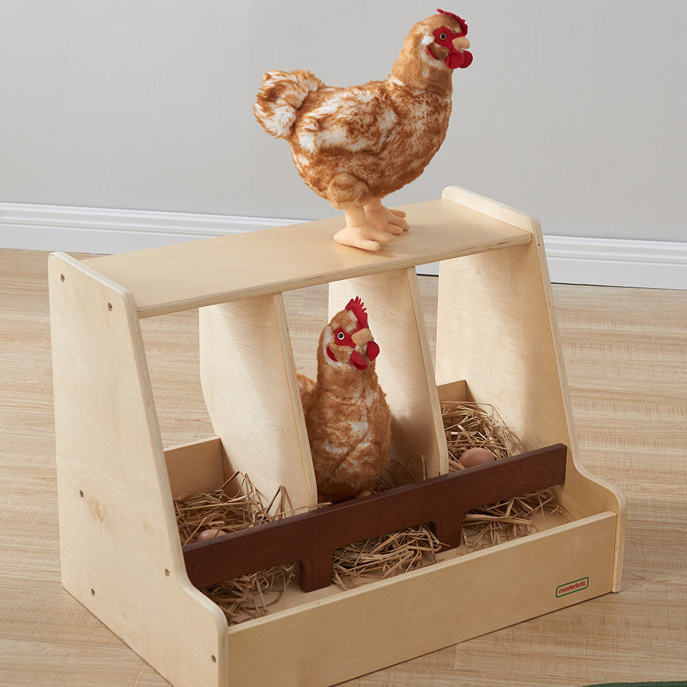 Child placing a play hen inside the wooden hen house.