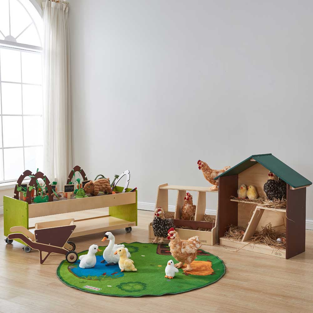 Child pushing the wooden wheelbarrow across the classroom floor.