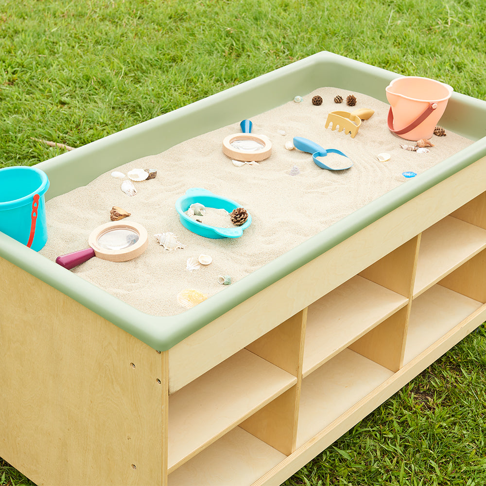 Preschoolers using the removable PE tray on the floor for a sand exploration activity.
