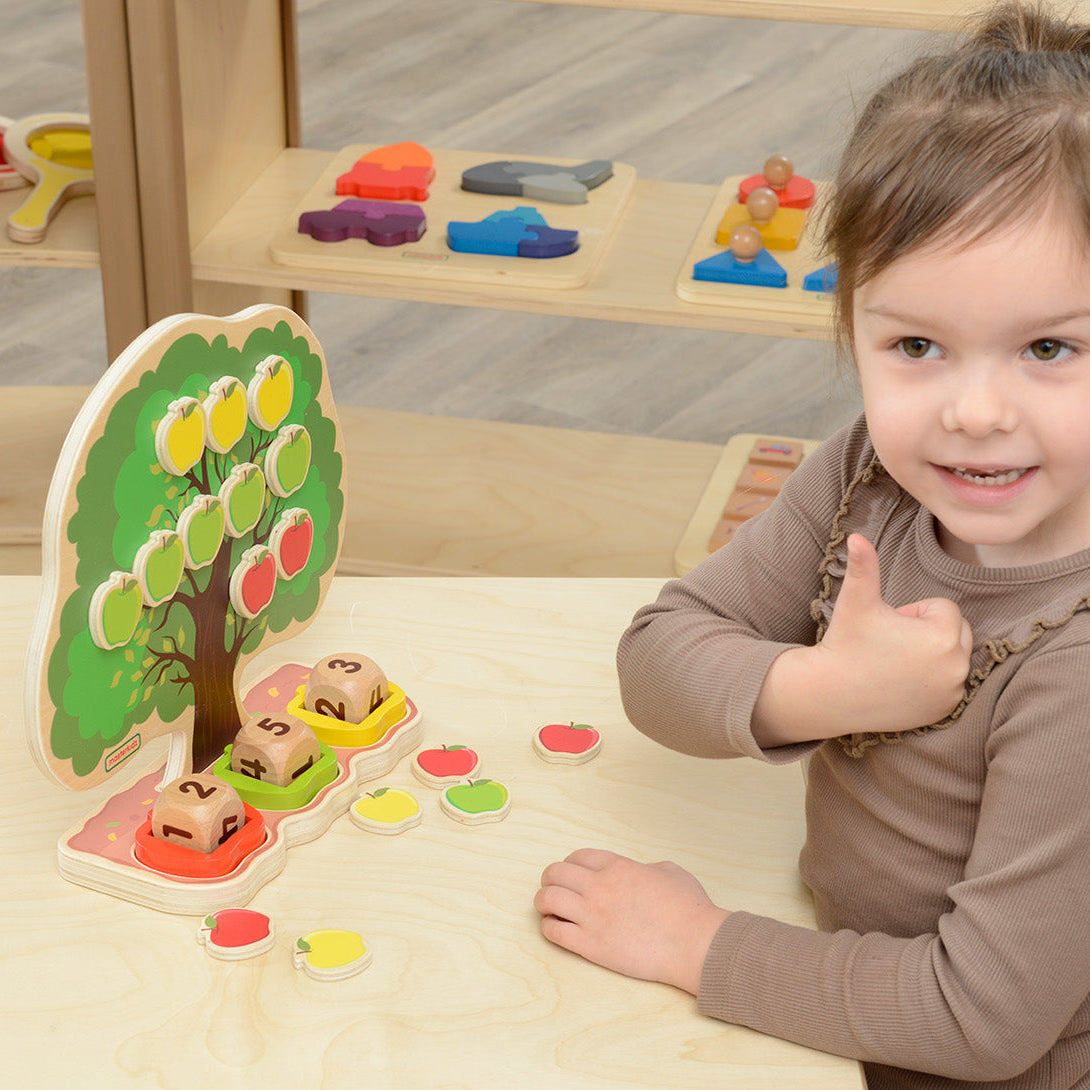 Child placing magnetic apples onto the apple tree for counting and learning.