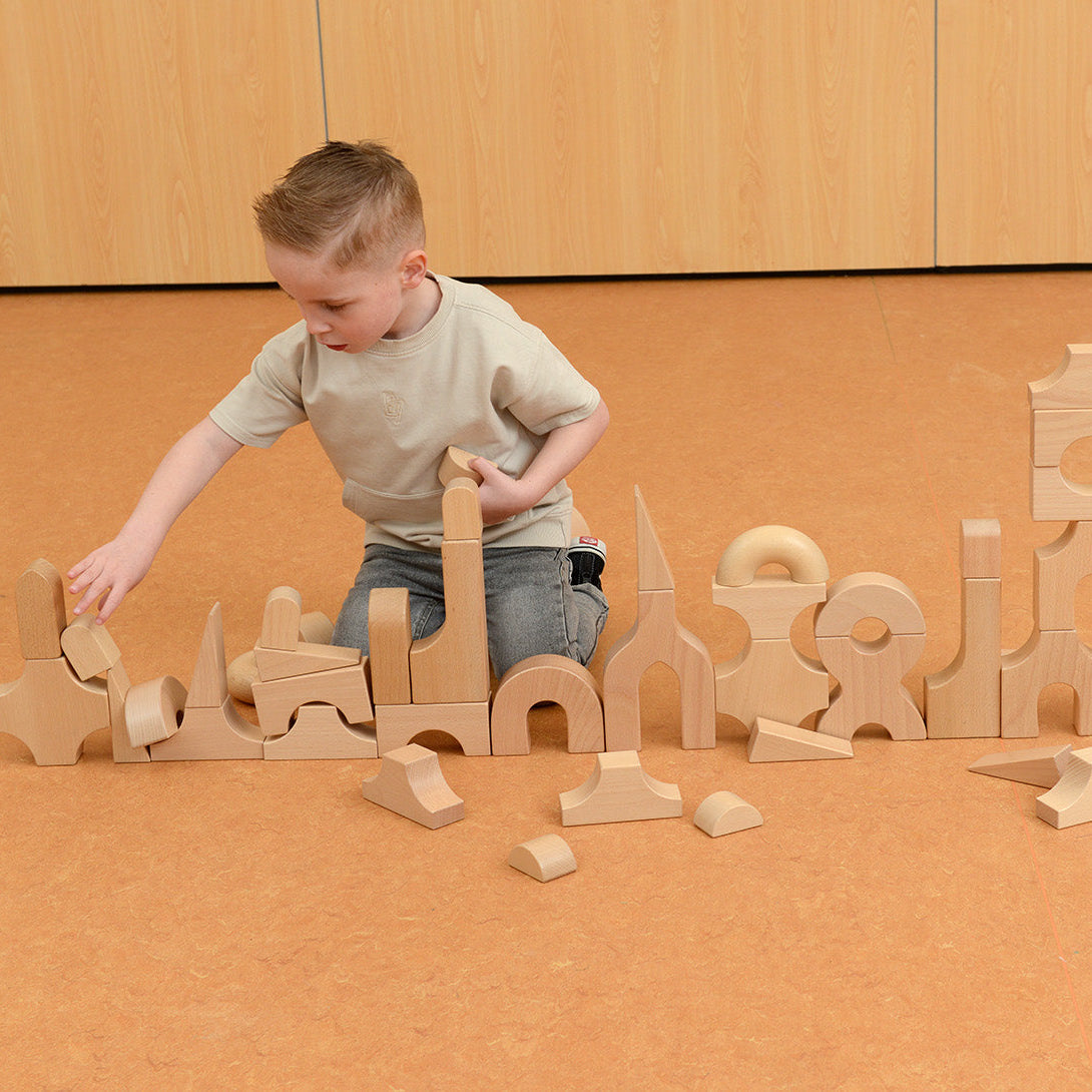 Teacher guiding students in a collaborative castle-building activity using the wooden block kit.