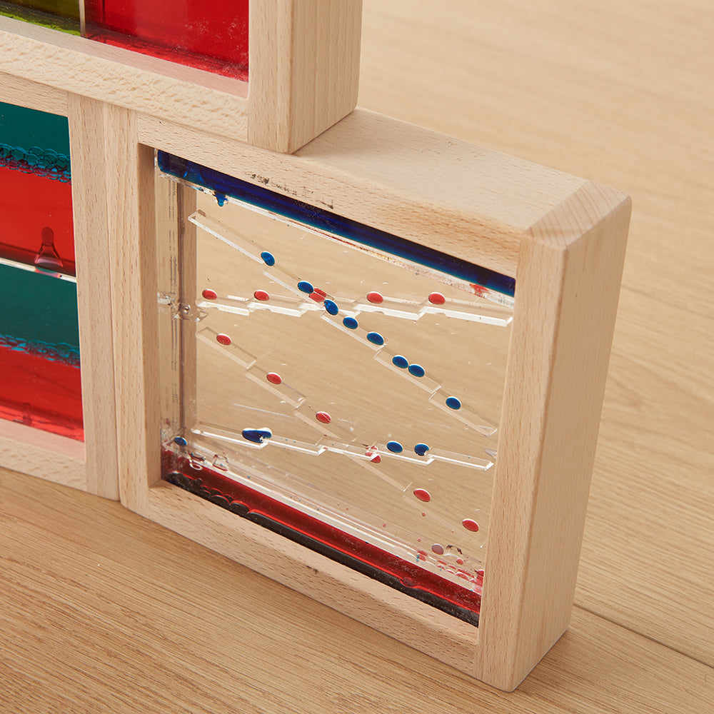 Liquid motion blocks arranged by shape and colour on a wooden table.