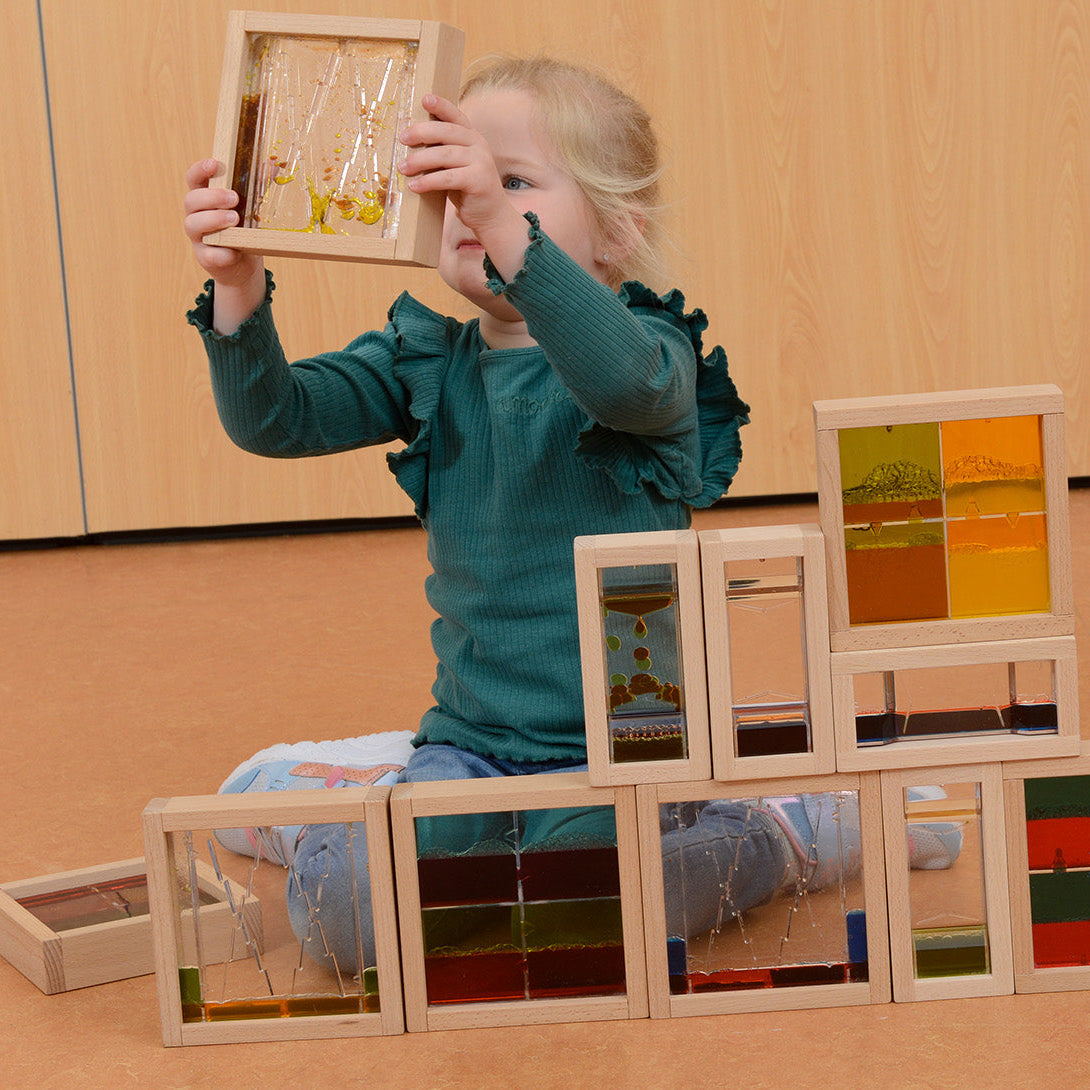 A child holding a block close to the eye to watch the liquid patterns.