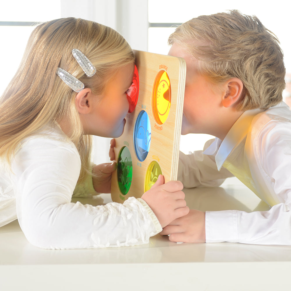 Child exploring the world through red, yellow, blue, green, and orange viewers.