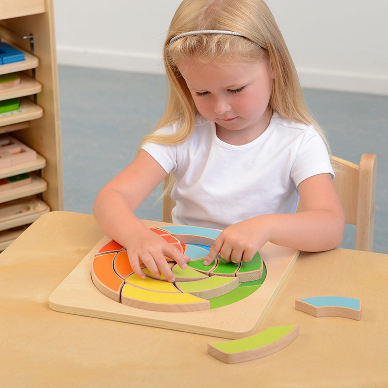 Child arranging spiral puzzle pieces into creative patterns on the board.