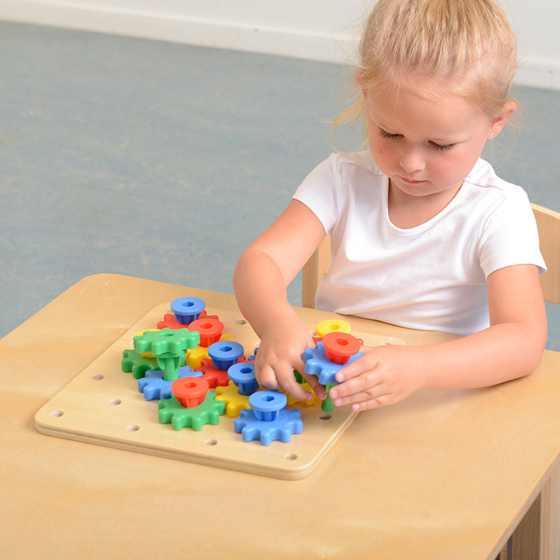 Preschool classroom scene with children engaging in gear-building play.