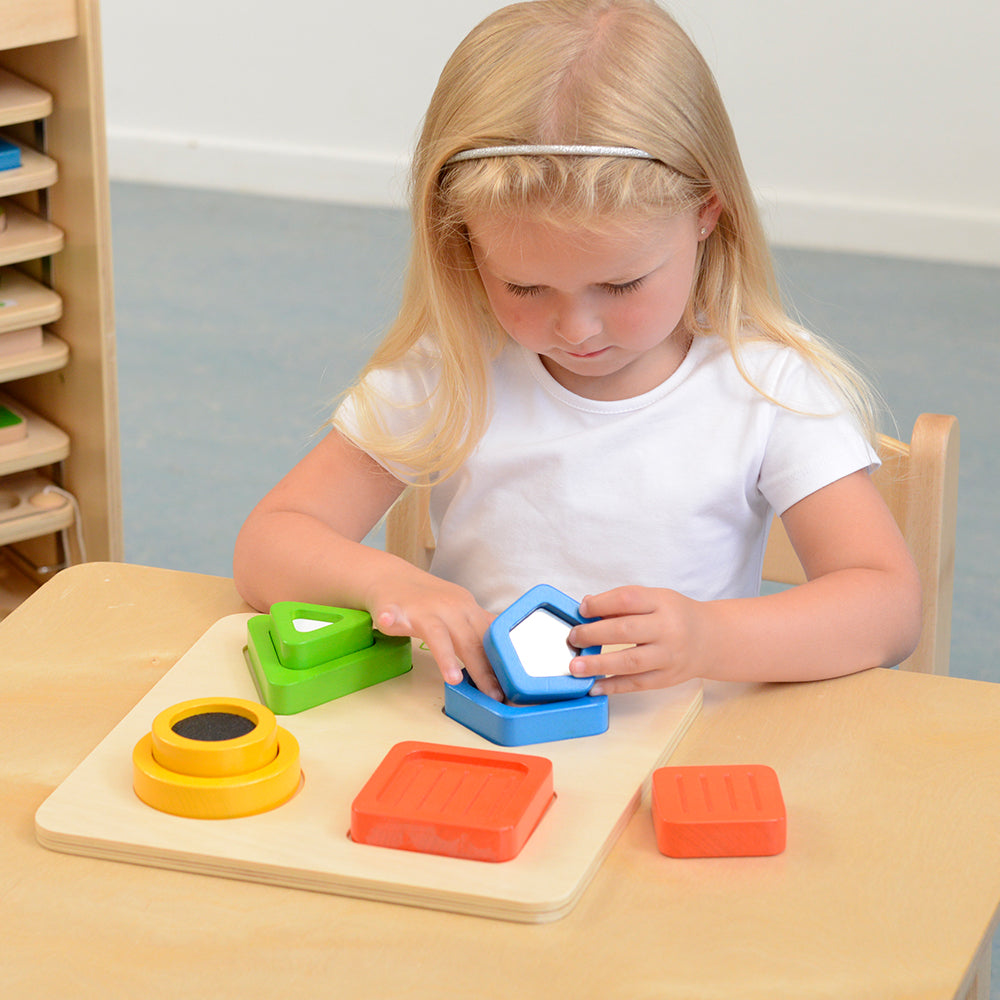 Child touching and feeling the textured blocks during a tactile matching activity.