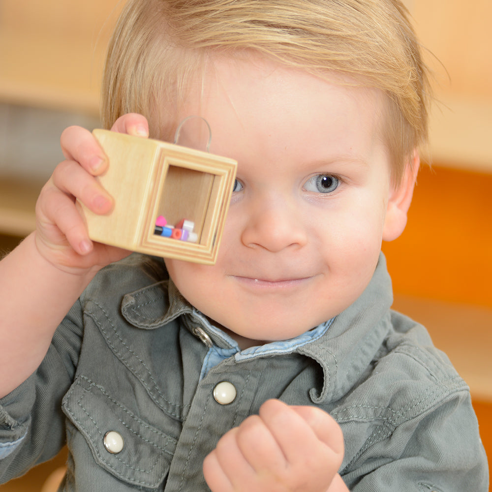 Preschool classroom scene with children practicing auditory discrimination using the cubes.