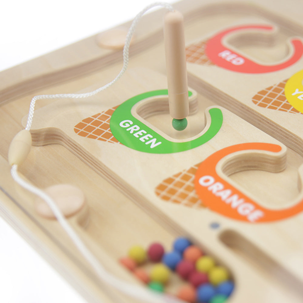 Child using the magnetic wand to guide beads through the maze for colour sorting.