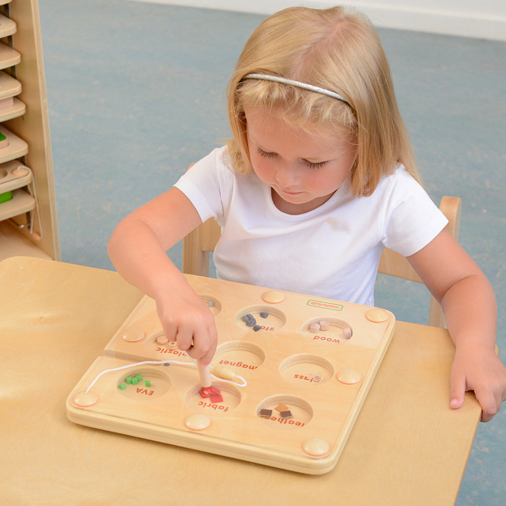 Child using the magnetic pen to test which materials are magnetic.