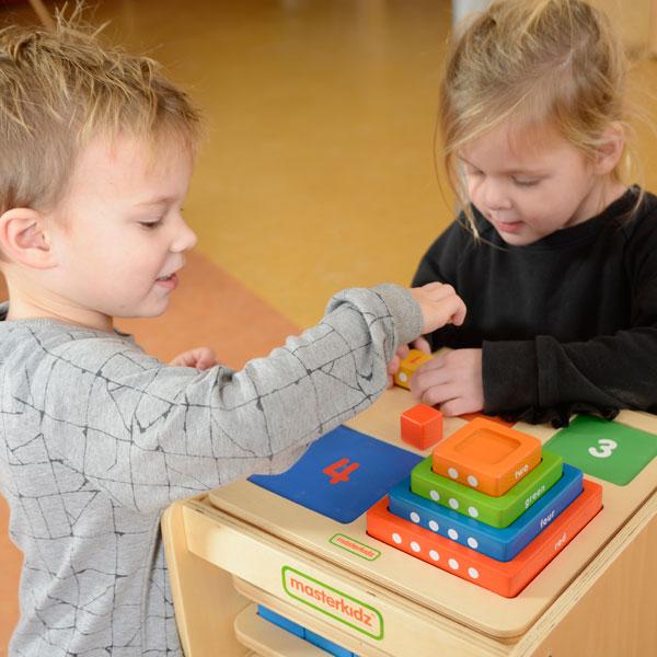 Children arranging blocks on the base panel for number sequencing from 1 to 5.