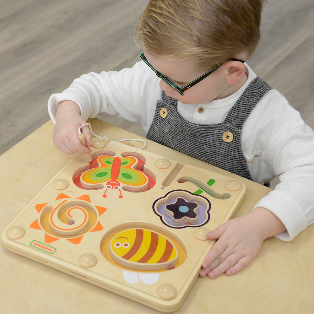 Child using magnetic pen to move beads along a spiral path.