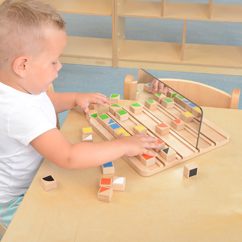Child exploring reflection patterns with colourful shape pieces.