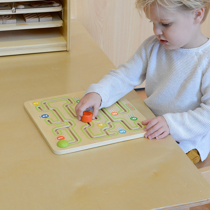 Child moving a peg along the maze for fine motor skill training.