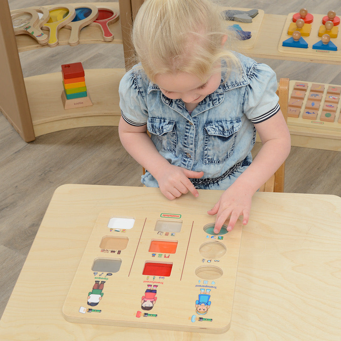 Child experimenting with light passing through transparent, translucent, and opaque objects on Masterkidz discovery board.