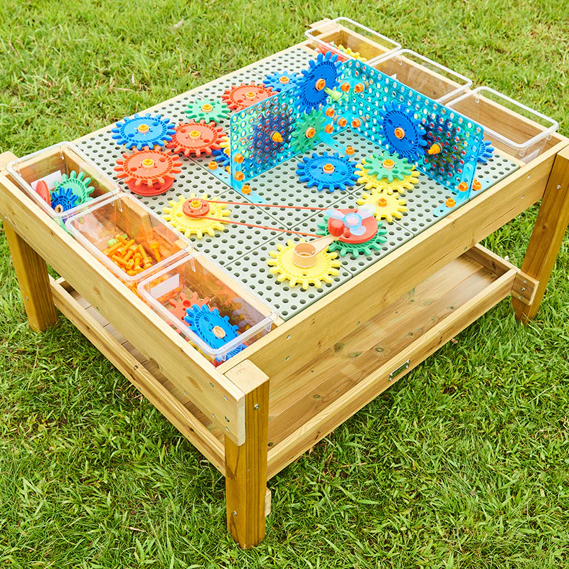Outdoor STEM Table with built-in storage tray holding gears, pegs, and building pieces.